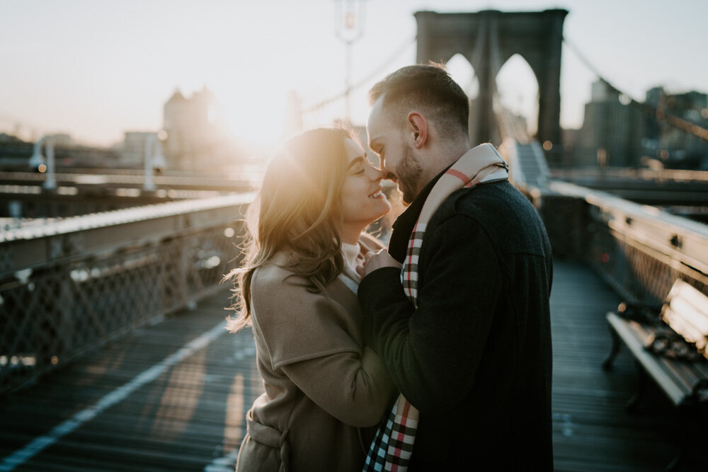 Couple kissing on brooklyn bridge at sunrise during engagement session