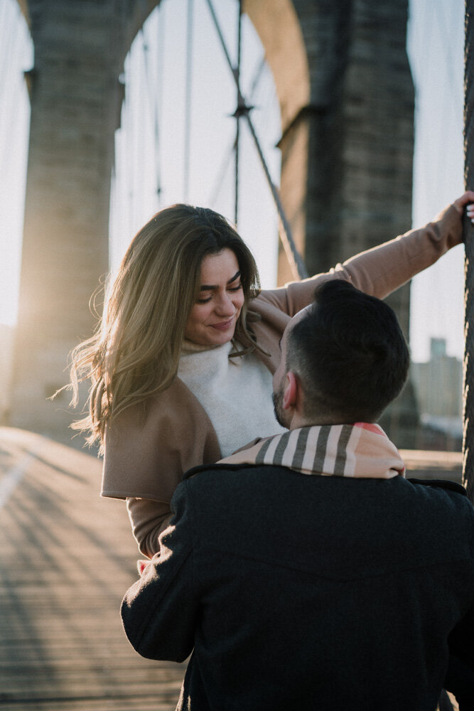 Man carries his girlfriend on brooklyn bridge during engagement session