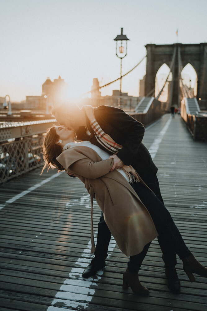 Couple kissing on brooklyn bridge at sunrise during engagement session