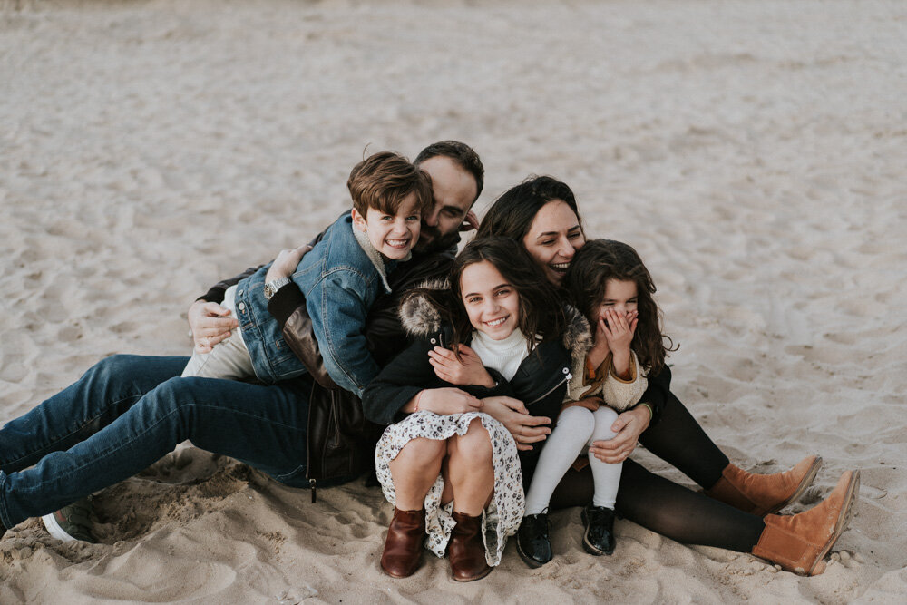 Parents and three kids laugh during family session at coney island beach