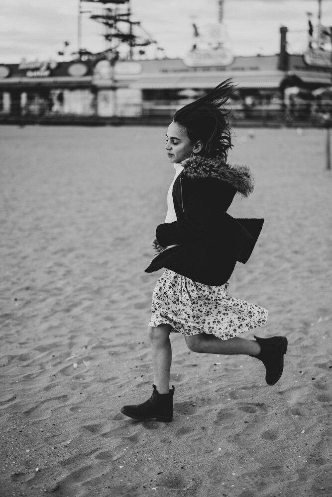 Young girl runs during family session at coney island beach