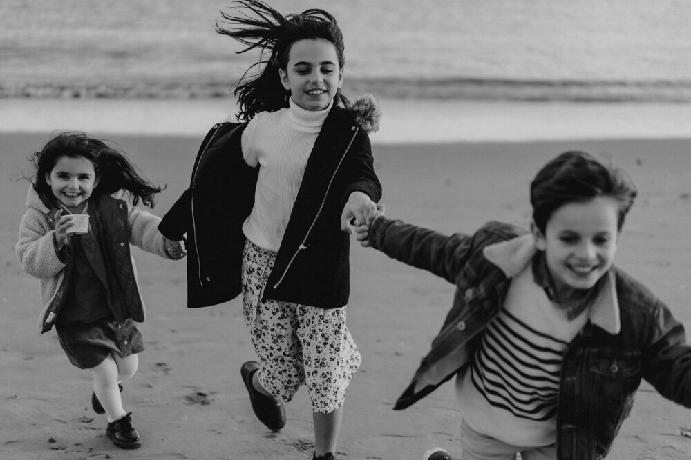 Three kids hold hands during family session at coney island beach
