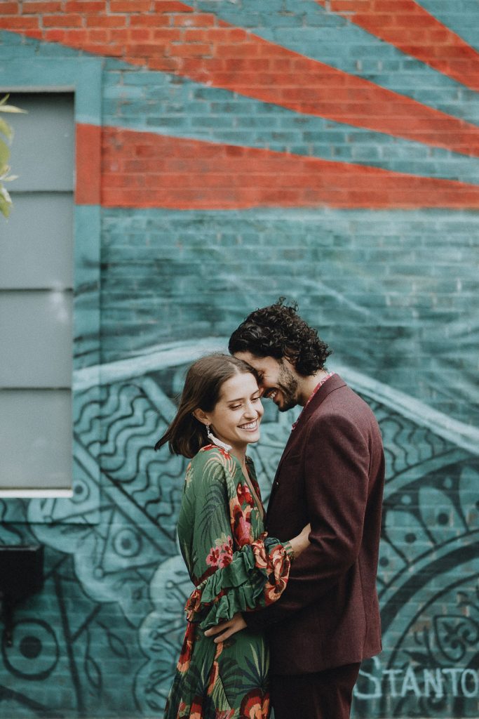 Couple laughs in front of brooklyn street art wall during elopement