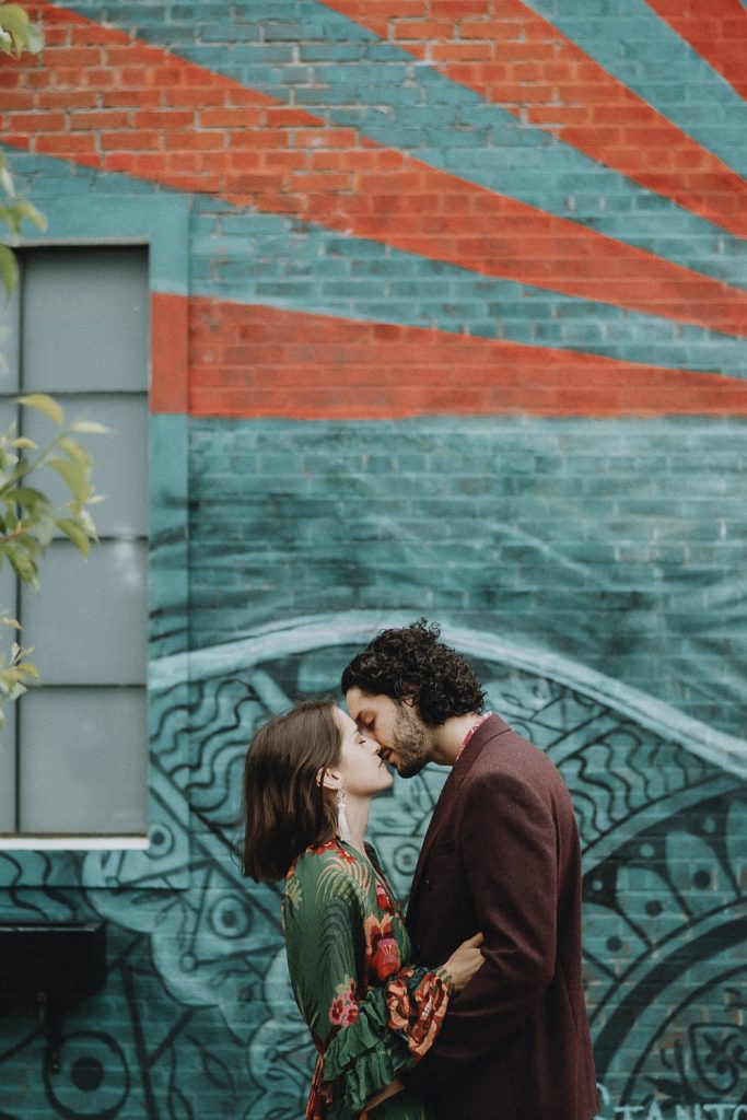 Couple kisses in front of brooklyn street art wall during elopement