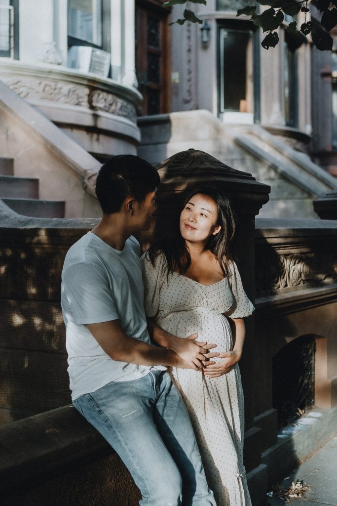 Expecting couple on brownstone steps during maternity session in prospect park