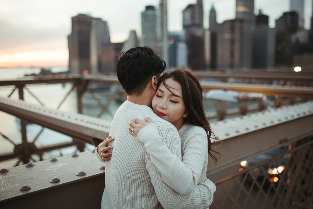Couple during engagement session on the brooklyn bridge at sunset