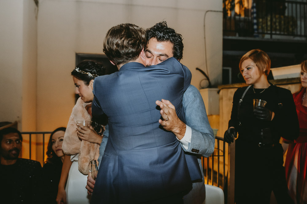 Groom hugs best man at brooklyn backyard wedding reception
