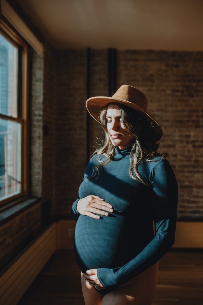 Pregnant woman with hat during maternity session in nyc home