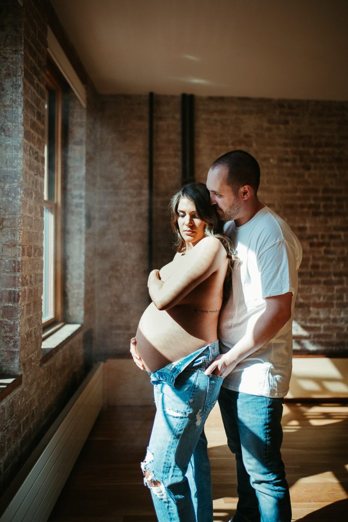 Expecting couple during intimate maternity session in nyc home