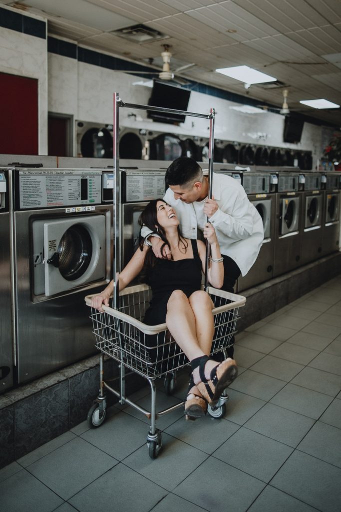 Couple during engagement photo session at laundromat in williamsburg