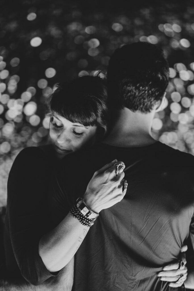Woman holds fiancé close during nightime engagement session in nyc