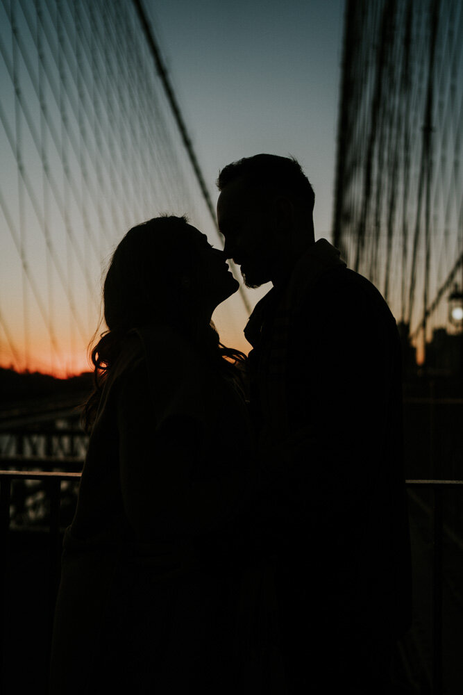 Silhouette of couple at sunrise on brooklyn bridge during engagement session