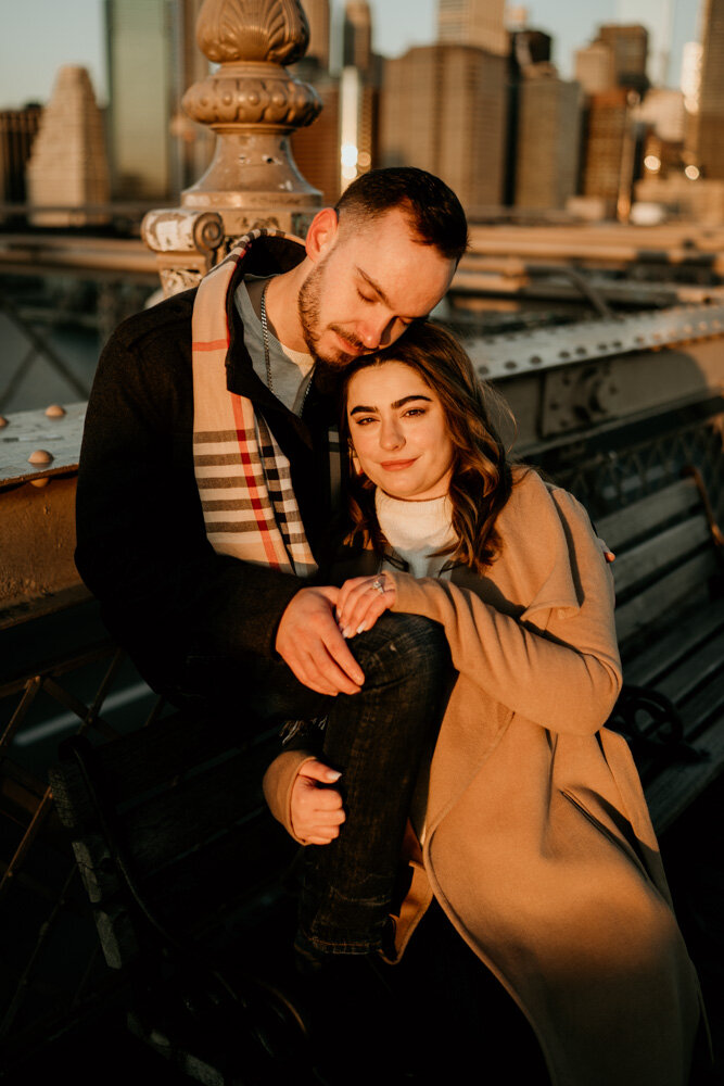 Couple snuggling on park bench at sunrise and looking at photographer