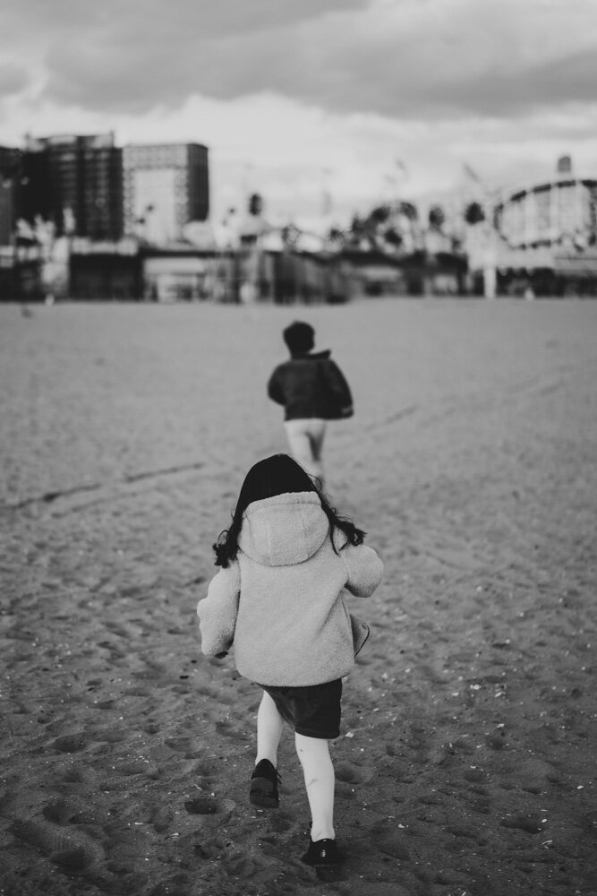 Brother and sister run during family session at coney island beach