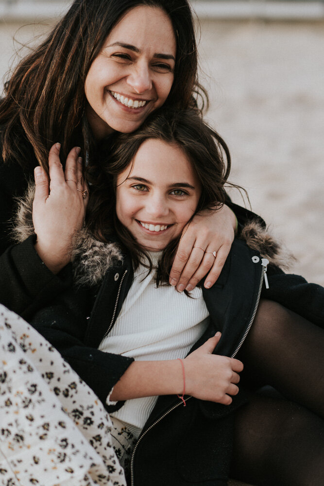 Mom and daughter laugh during family session at coney island beach