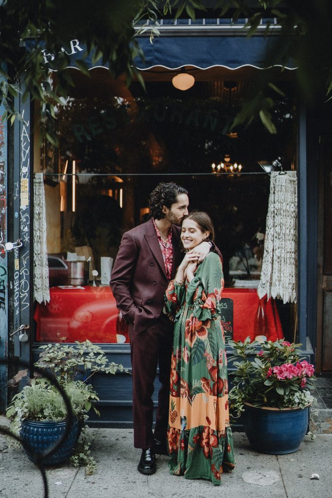 Groom kisses bride in front of brooklyn restaurant during elopement