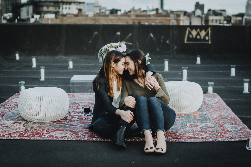 Lesbian couple snuggling on rooftop during nyc engagement photoshoot