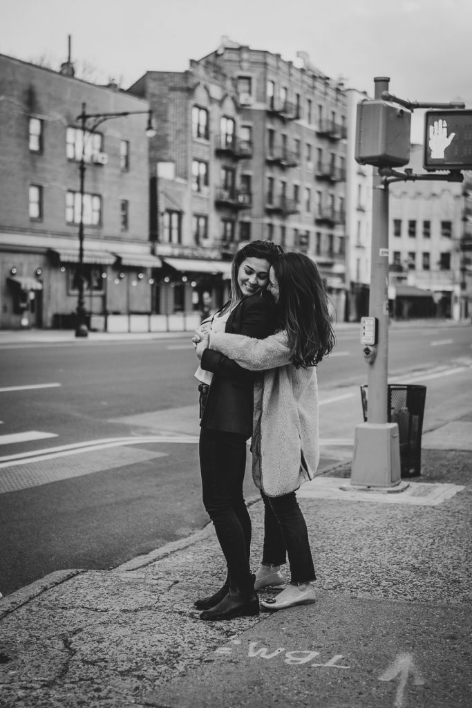 Lesbian couple snuggling in nyc street during engagement session