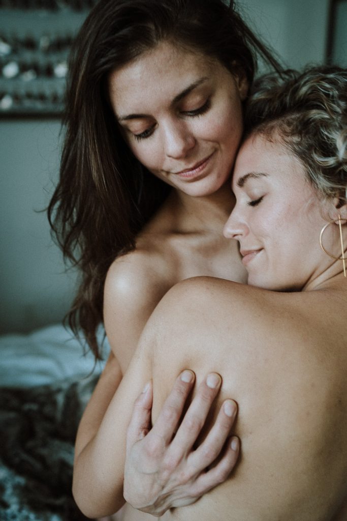Lesbian couple snuggling naked during couple session in their brooklyn home