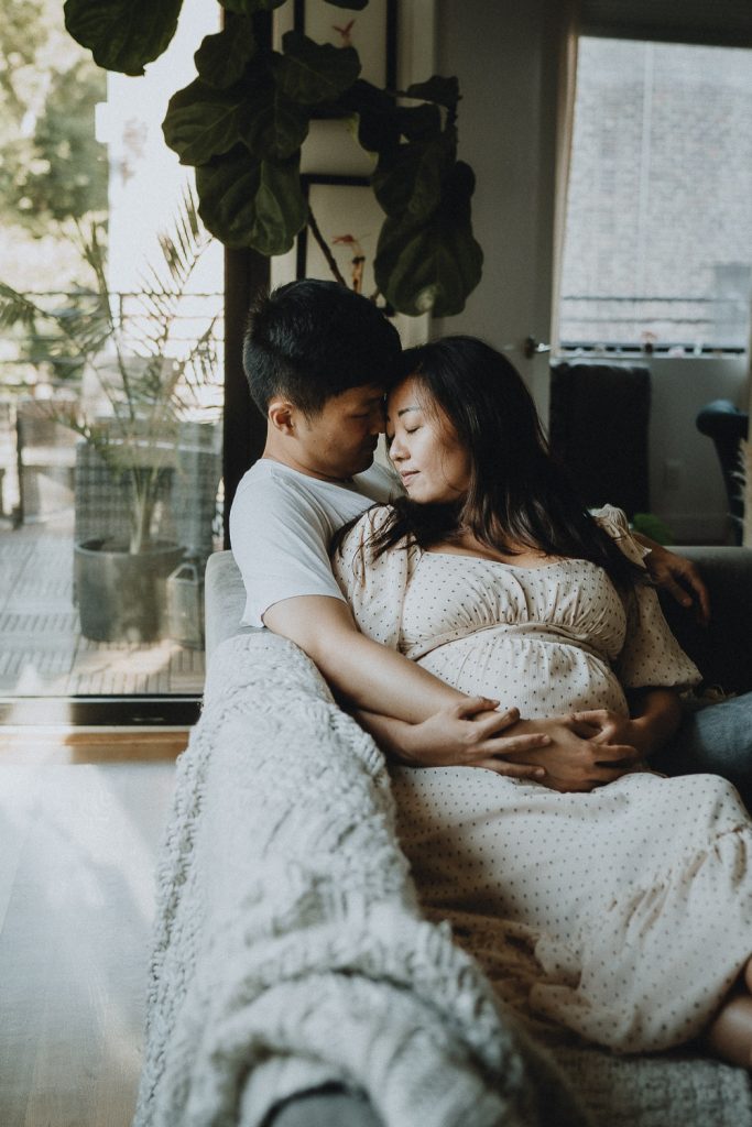 Expecting couple snuggling at home during maternity session in brooklyn