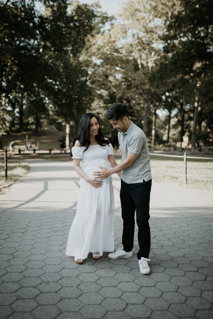 Expecting couple touches baby bump in central park during maternity photoshoot
