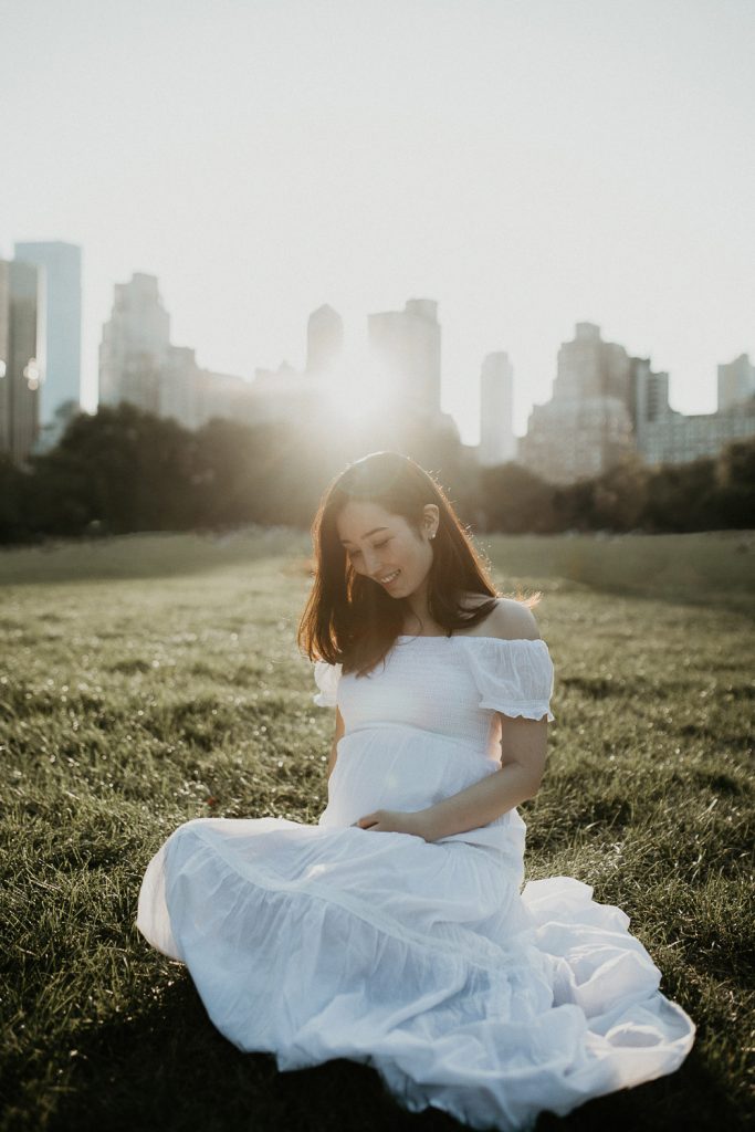 Pregnant woman in central park at golden hour during maternity photoshoot