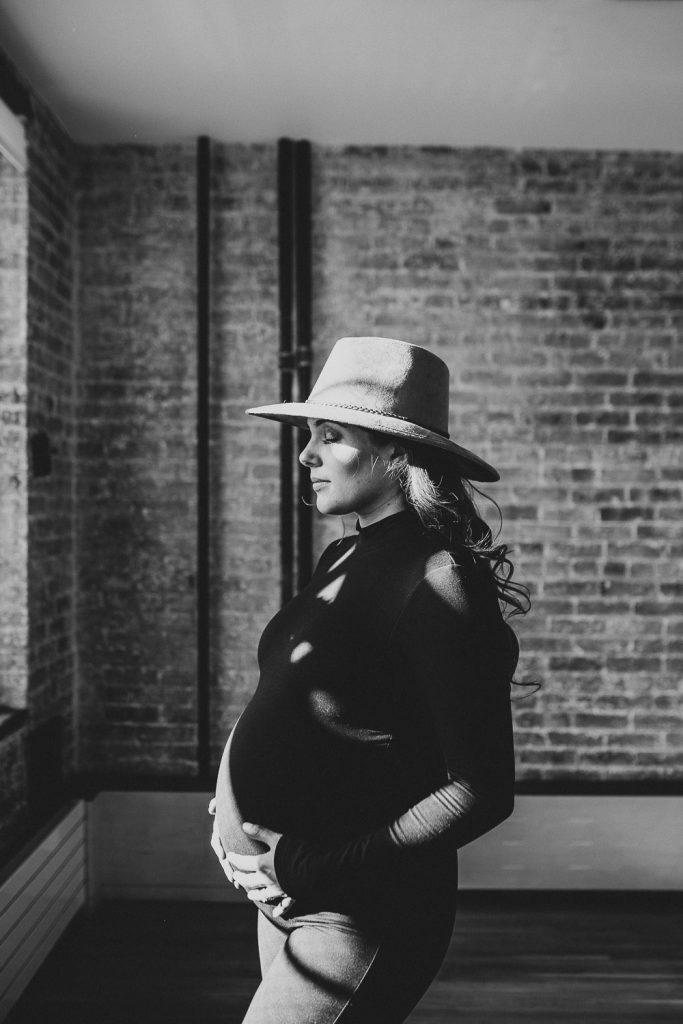 Pregnant woman with hat during maternity session in nyc home