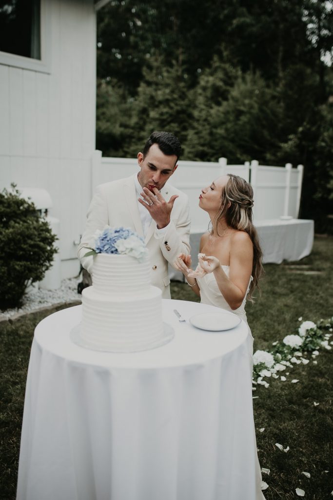Bride and groom cut cake at backyard wedding in the hamptons