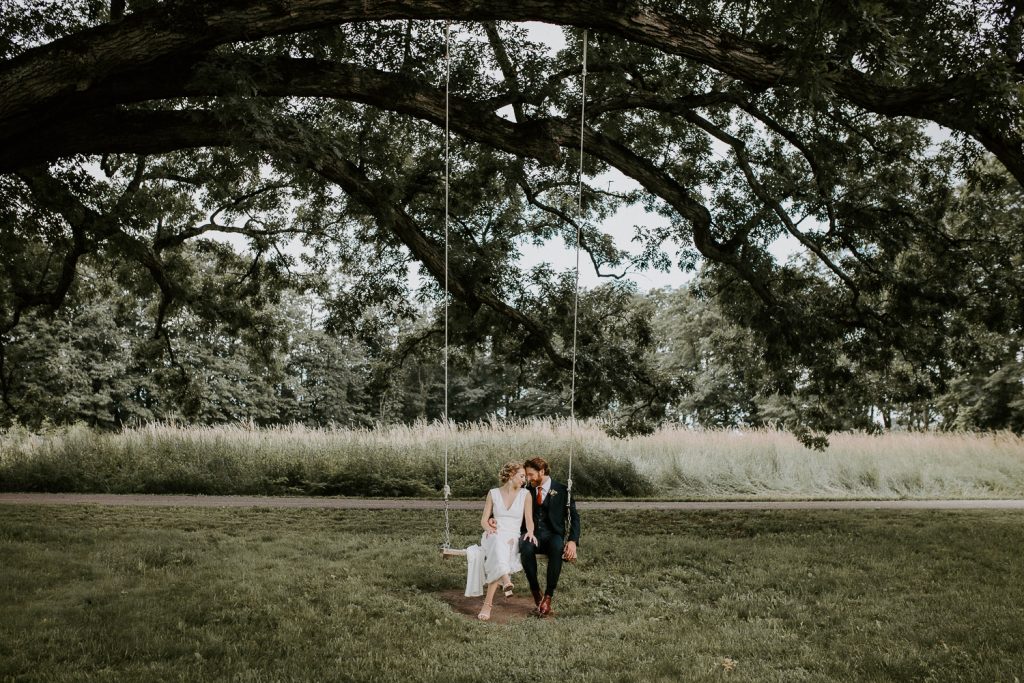 Bride and groom on swing at red maple vineyard