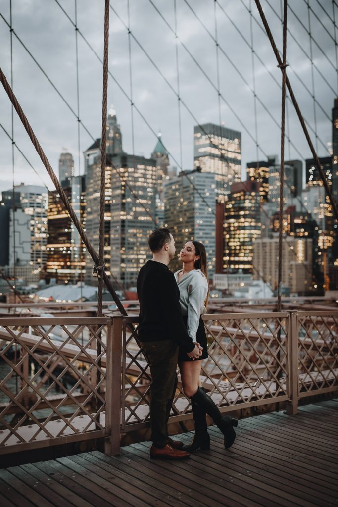 Couple during engagement photoshoot at night on brooklyn bridge