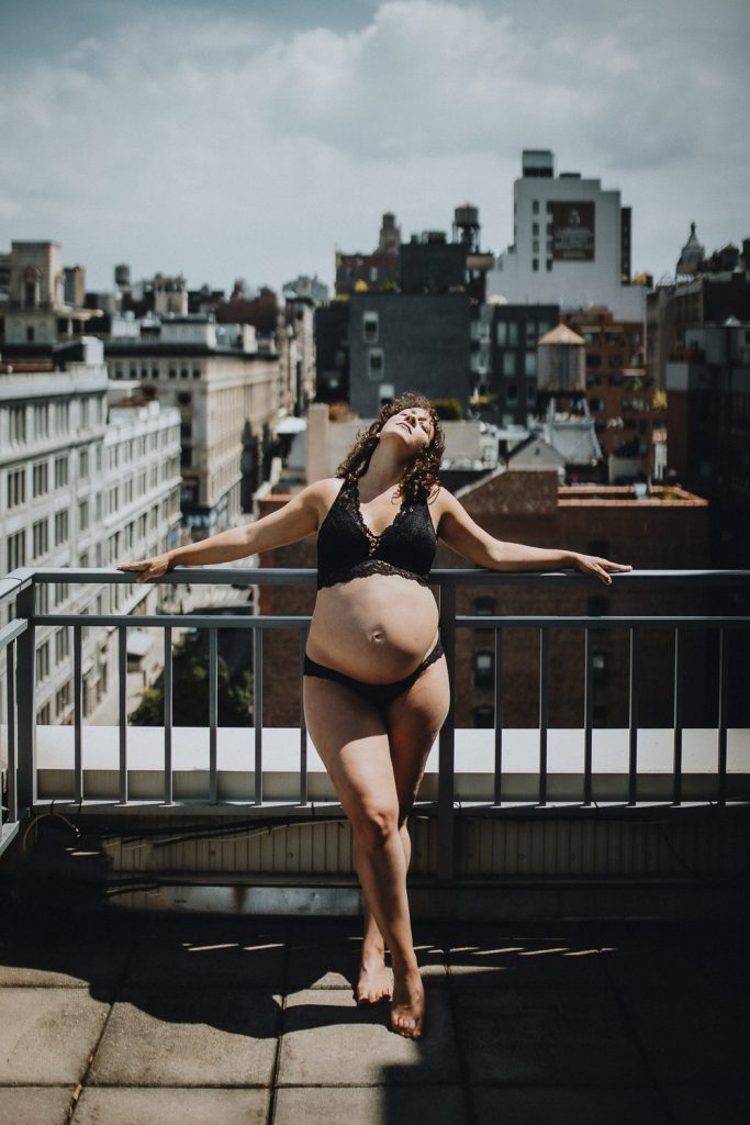 Pregnant woman on nyc rooftop during intimate maternity session at home
