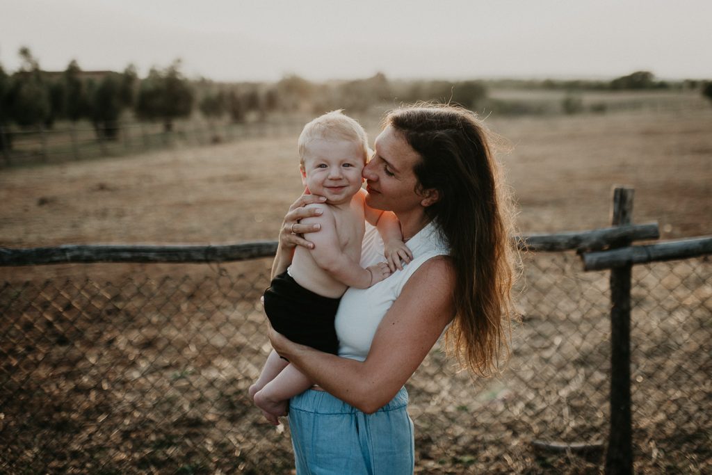 Motherhood photoshoot with baby in countryside at golden hour