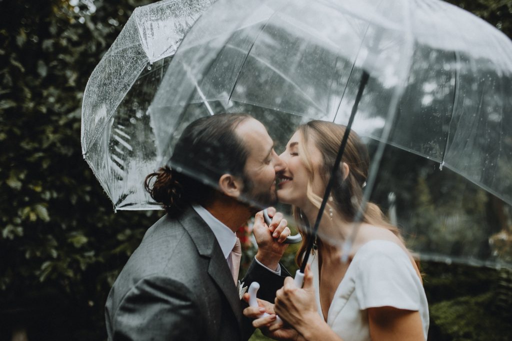 Bride and groom under transparent umbrella at rainy nyc wedding