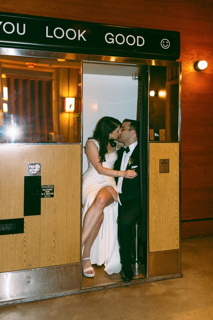 Bride and groom kissing in vintage photobooth