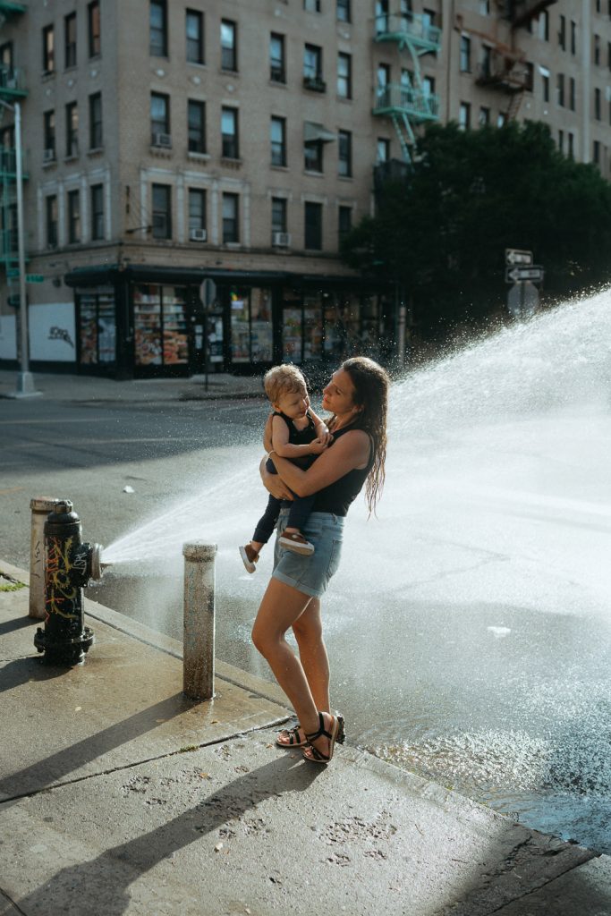 Mother and son playing with fire hydrant water during brooklyn summer