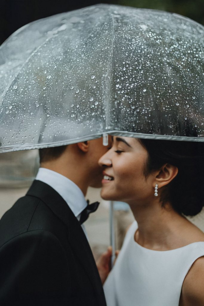 Bride and groom under umbrella during rainy nyc elopement